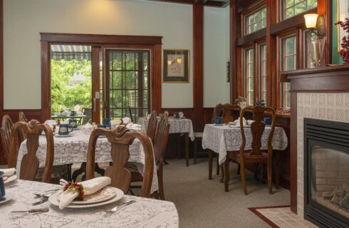 Large dining room with multiple wooden tables and chairs and a fireplace