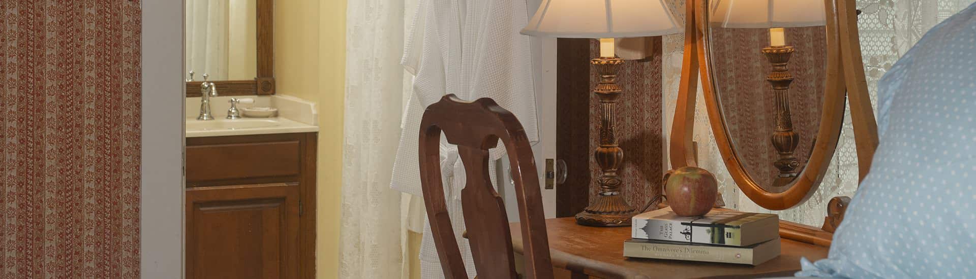 Close up view of wooden chair and wooden desk with books, apple, and lamp in a bedroom